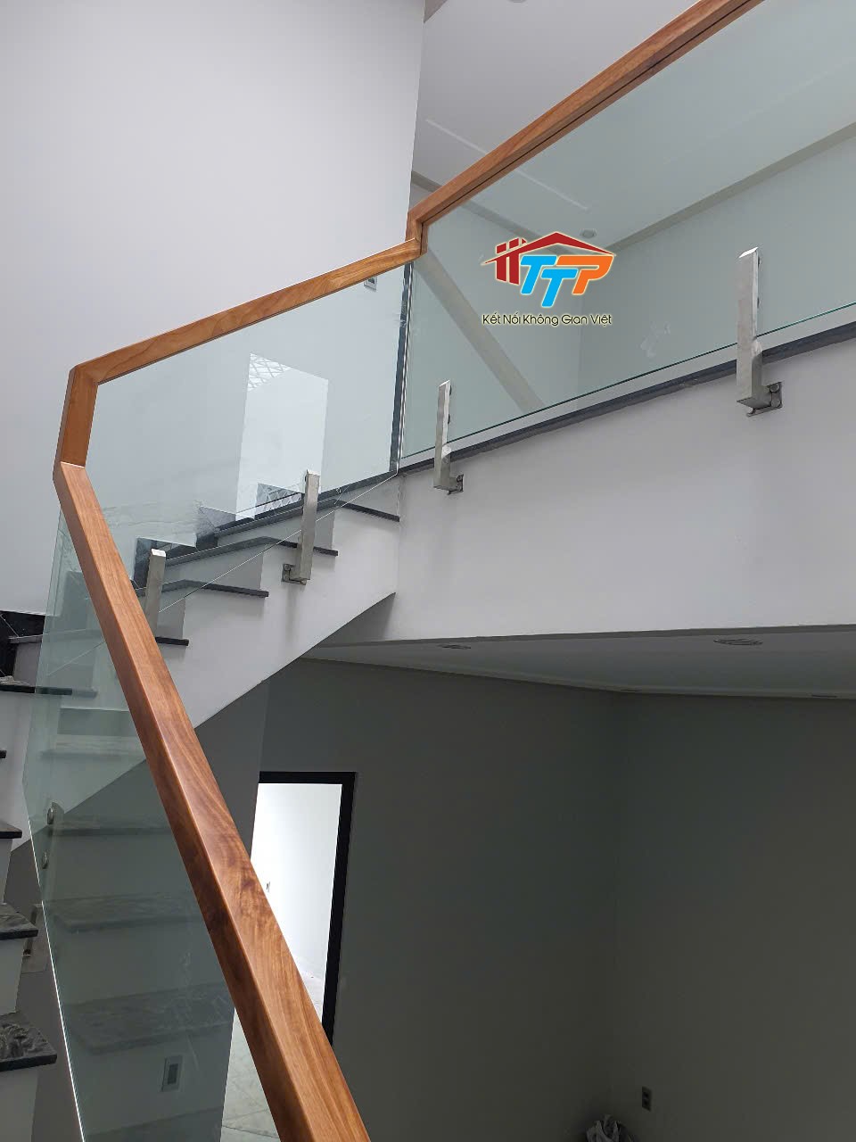 Cầu thang kính cường lực tay vịn gỗ căm xe trụ inox lửng
